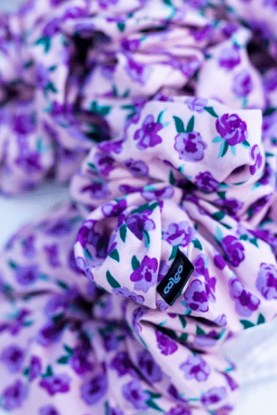 Detailní pohled na gumičku Purple Blossom z viskózy s fialovým květinovým potiskem a černým štítkem Caloo