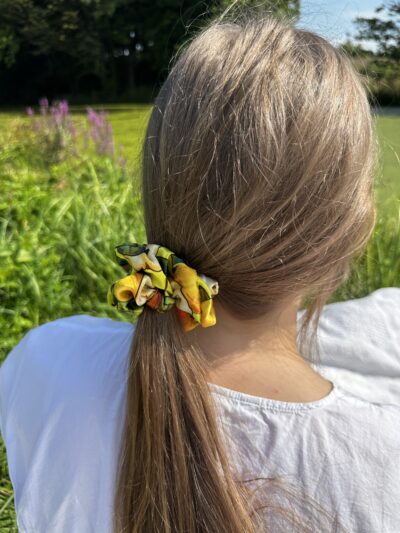 Detailní pohled na ručně šitou gumičku Sweet Pear z viskózy ve světlých vlasech, přirozené světlo.