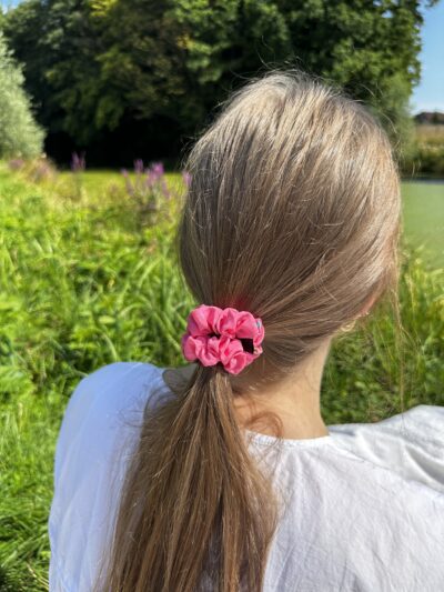 Scrunchie z kolekce rosy star zachycená z profilu ve vlasech, s výrazným vzorem a hedvábným leskem.