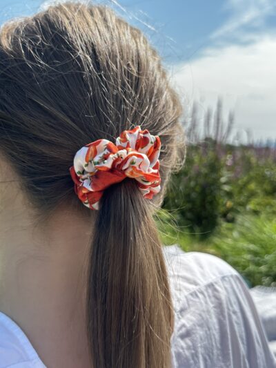 Ručně šitá scrunchie strawberry bliss ve vlasech, zapletený cop, přírodní materiál, styling v přírodě.